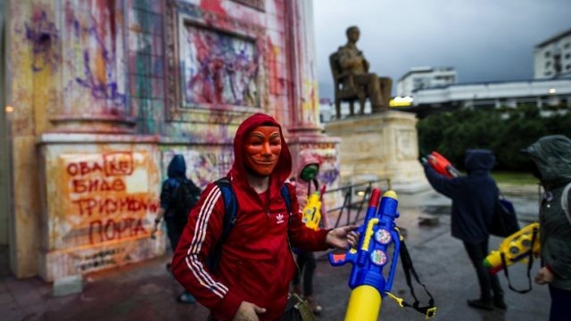 متظاهرون يرشون لونا على تمثال بوابة النصر في مقدونيا ببنادق مائية (AFP)