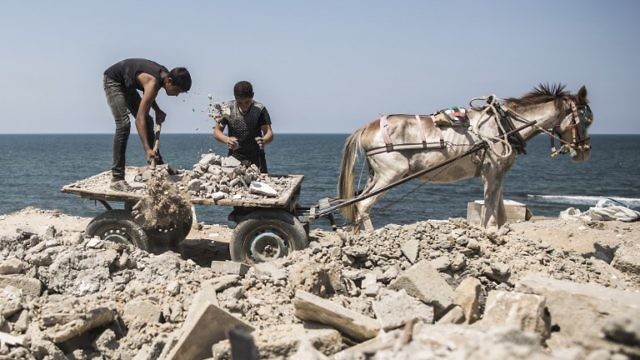 أطفال فلسطينيون في غزة يجمعون مهملات بغرض بيعها (AFP)