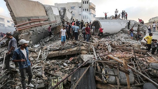 فلسطينيون يقفون على حطام مبنى قصفه سلاح الجو الإسرائيلي في وسط غزة (AFP)