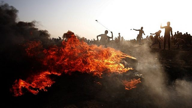 متظاهرون فلسطينيون يرشقون الحجارة باتجاه القوات الإسرائيلية خلال اشتباكات على طول السياج الحدودي الإسرائيلي ، شرق مدينة غزة في 28 سبتمبر 2018 (AFP)