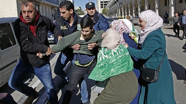 قوات الأمن الفلسطينية تشتبك مع أنصار حماس خلال مظاهرة بمناسبة الذكرى الحادية والثلاثين لتأسيس الحركة، في مدينة الخليل (AFP)